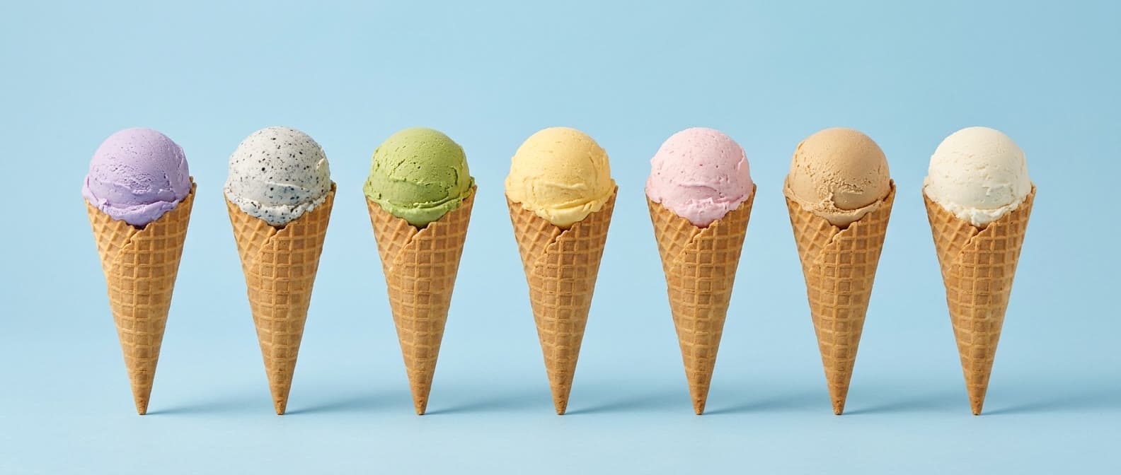 A row of seven Sweet Dynasty flavors on waffle cones